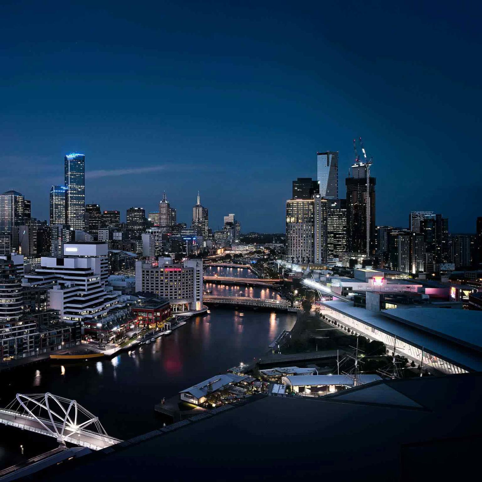 Night time aerial shot of the city with the Melbourne Convention and Exhibition Centre and Yarra River in the foreground. 