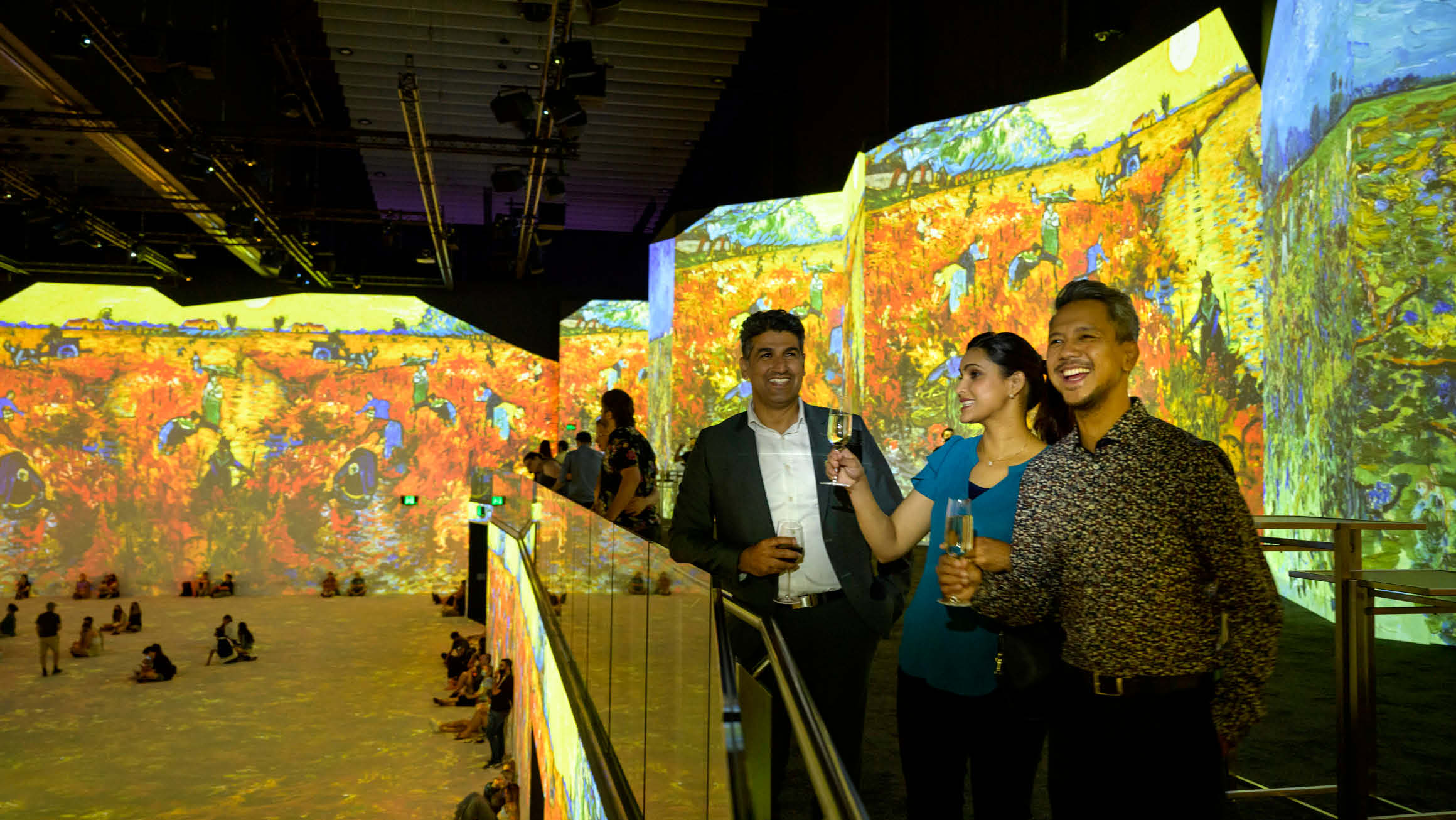 View of the mezzanine level at THE LUME Melbourne with focus on three people smiling drinking champagne. 