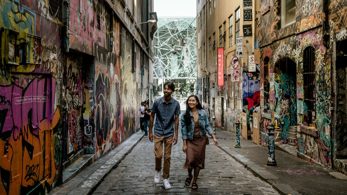 Two people walking up a laneway full of graffiti. 