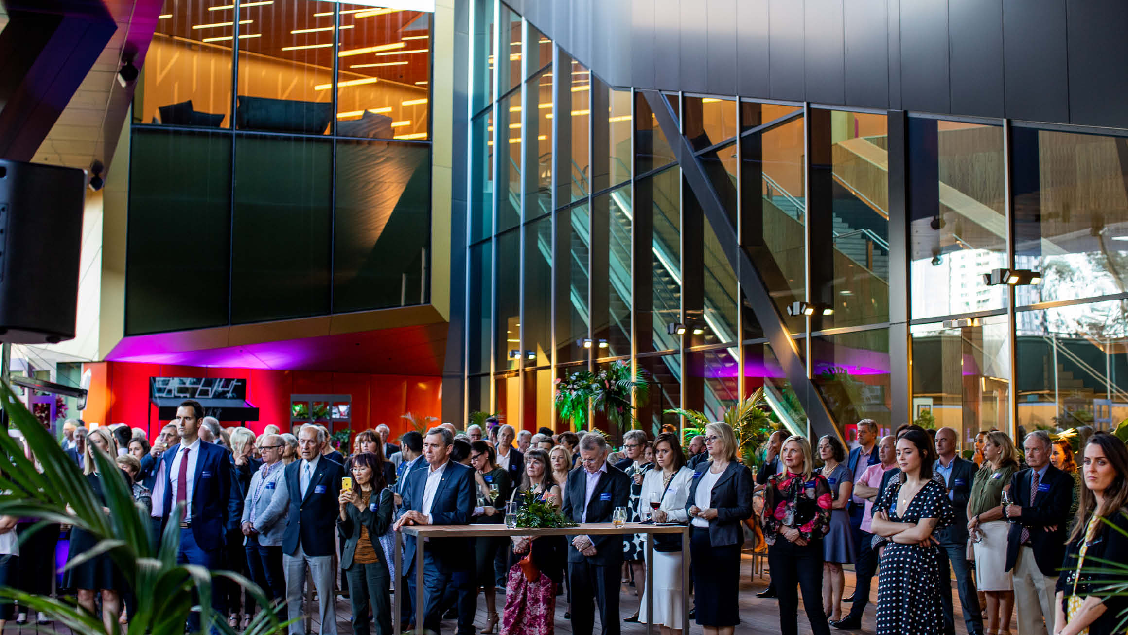 A large crowd of people are gathered in an outdoor courtyard, all staring intently at something. 