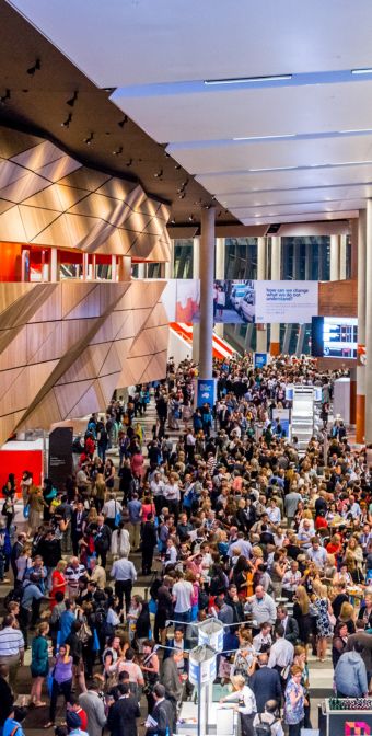 Convention Centre foyer filled with lots of people walking around. 