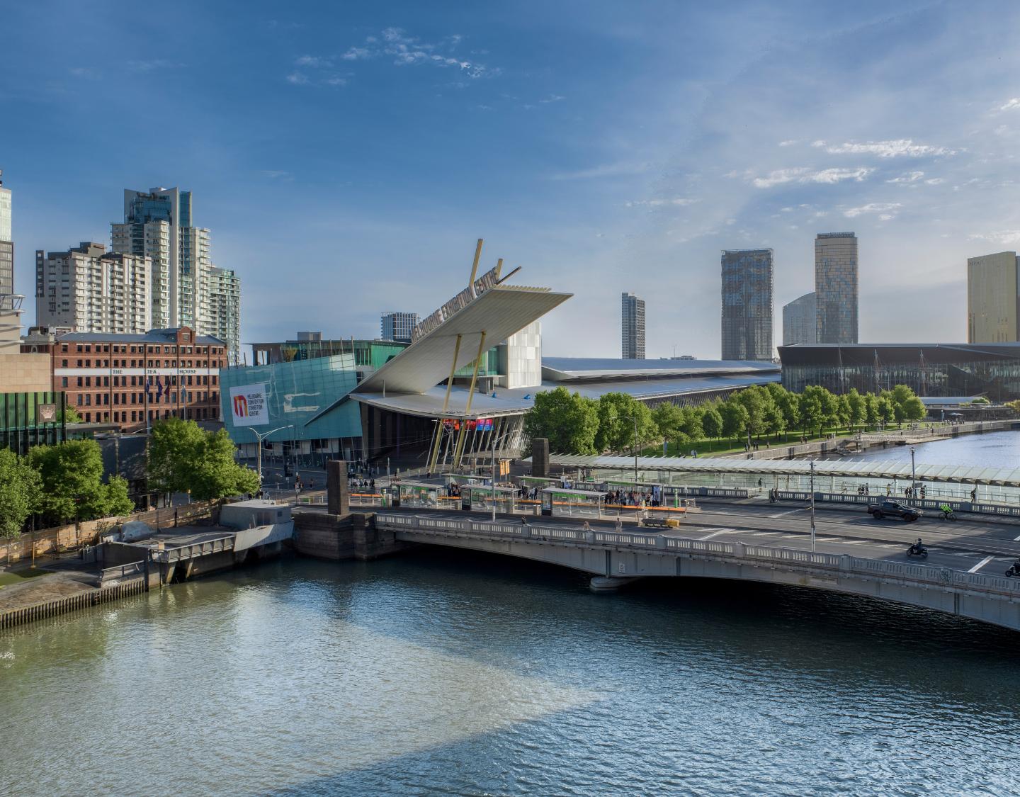 Outside MCEC, Clarendon Street entrance. Bird's view of the bridge over the Yarra River. Bright blue sky in the background and sun shining from off screen. 