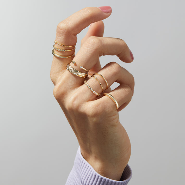 hand with stacked gold rings on each finger