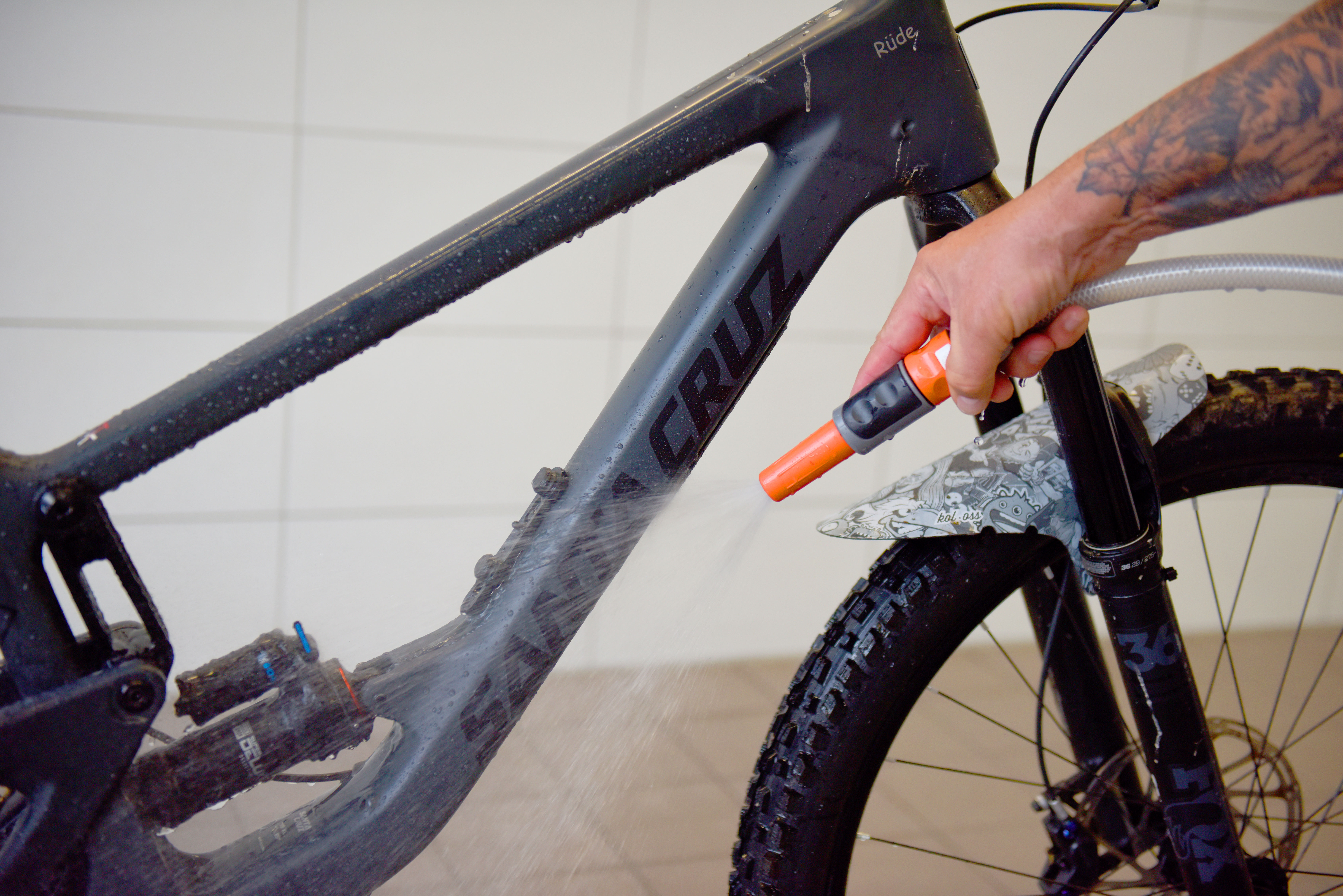 Fahrrad reinigen: Fahrrad wird mit einem Schlauch und klarem Wasser abgewaschen