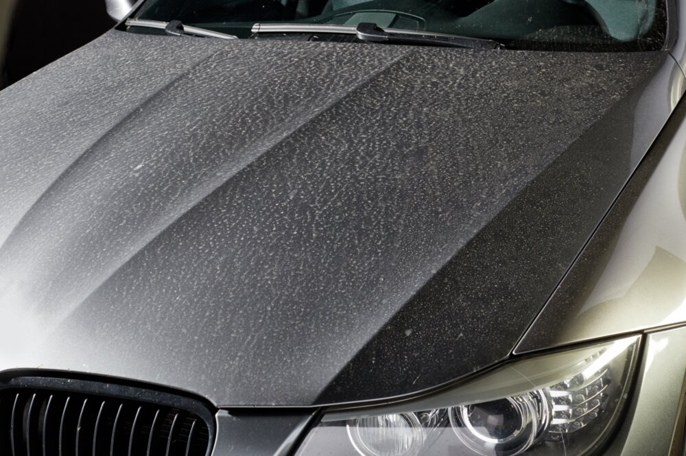 Ein graues Auto mit Saharastaub auf der Motorhaube.