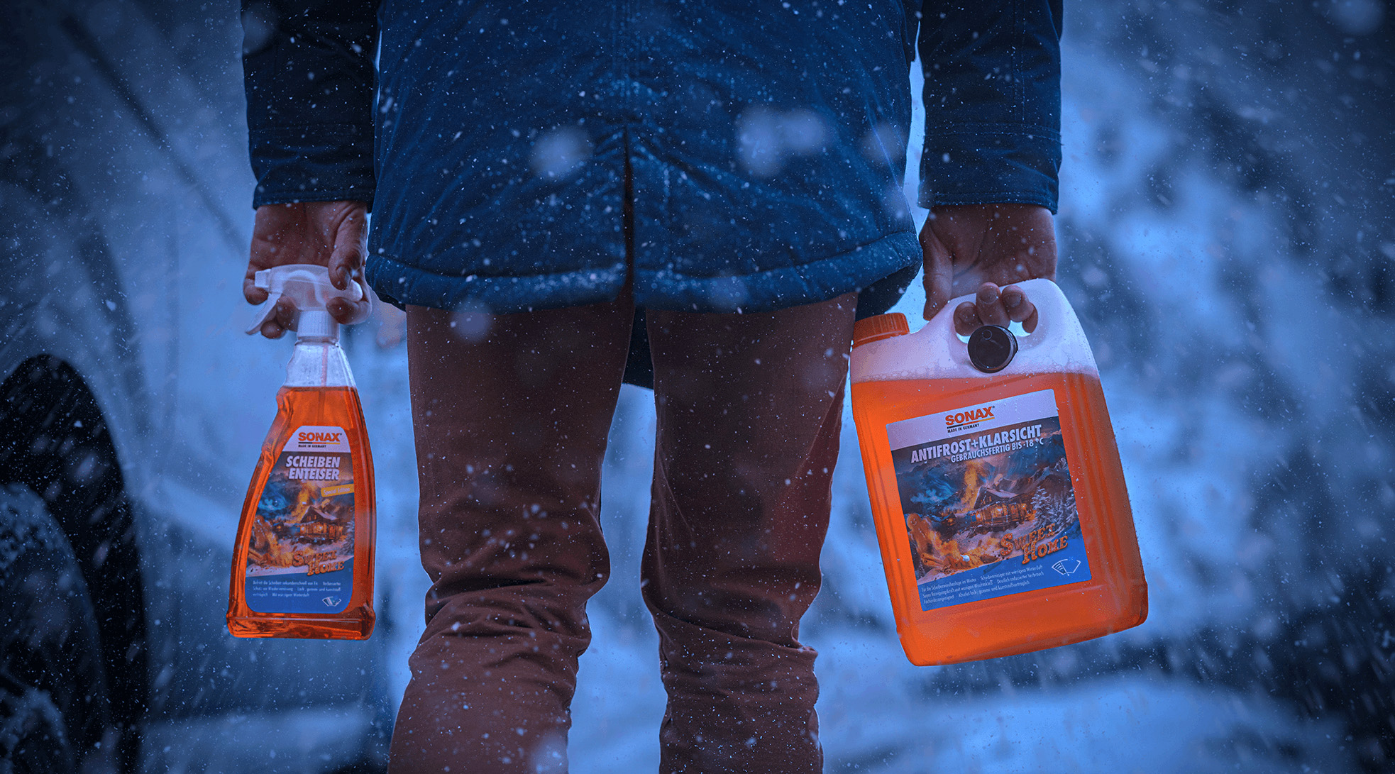 In einer dunklen Winterlandschaft trägt ein Mann den Sweet Home ScheibenEnteiser und AntiFrost+KlarSicht.