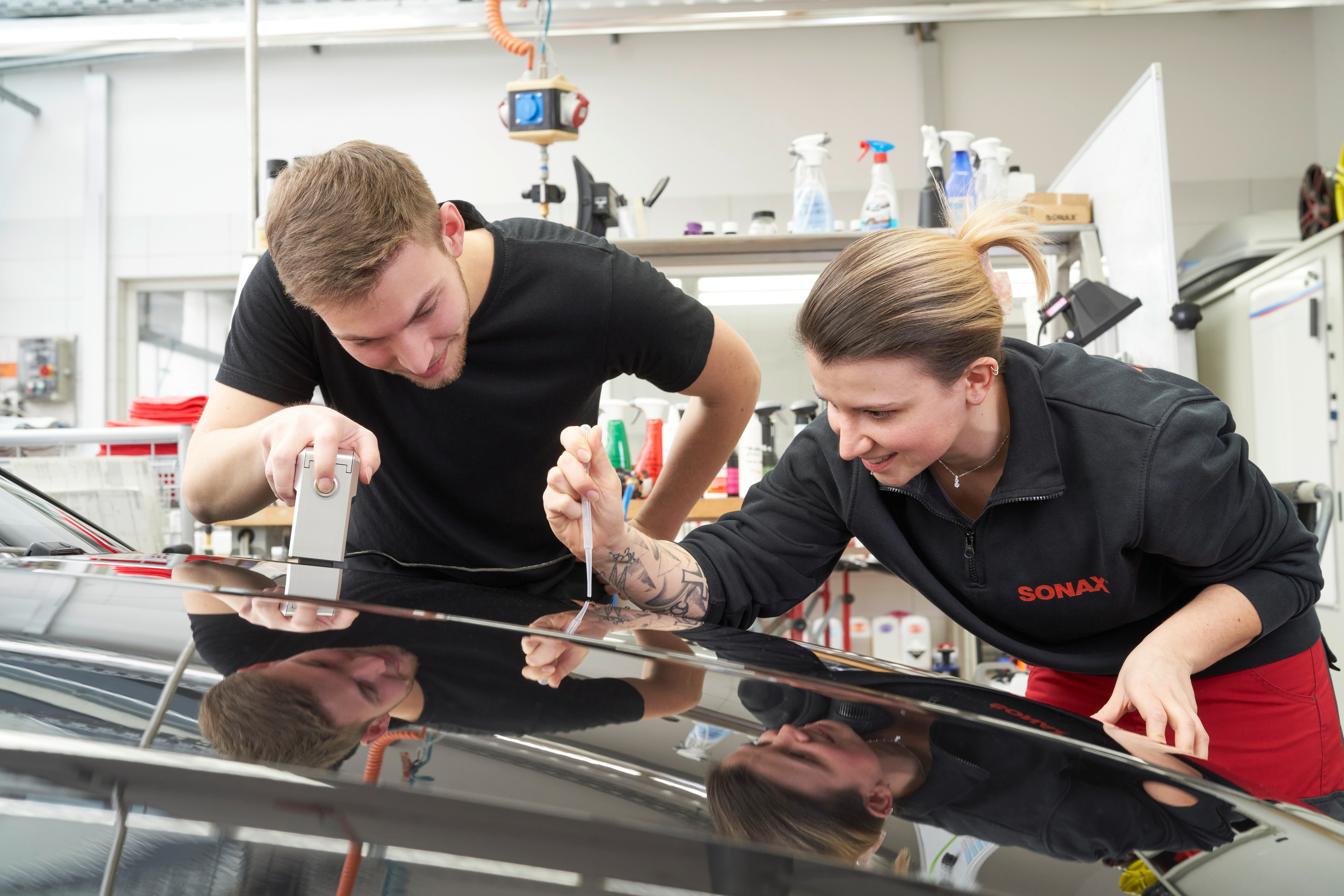 Mitarbeiter der Anwendungstechnik arbeiten an einem Auto.