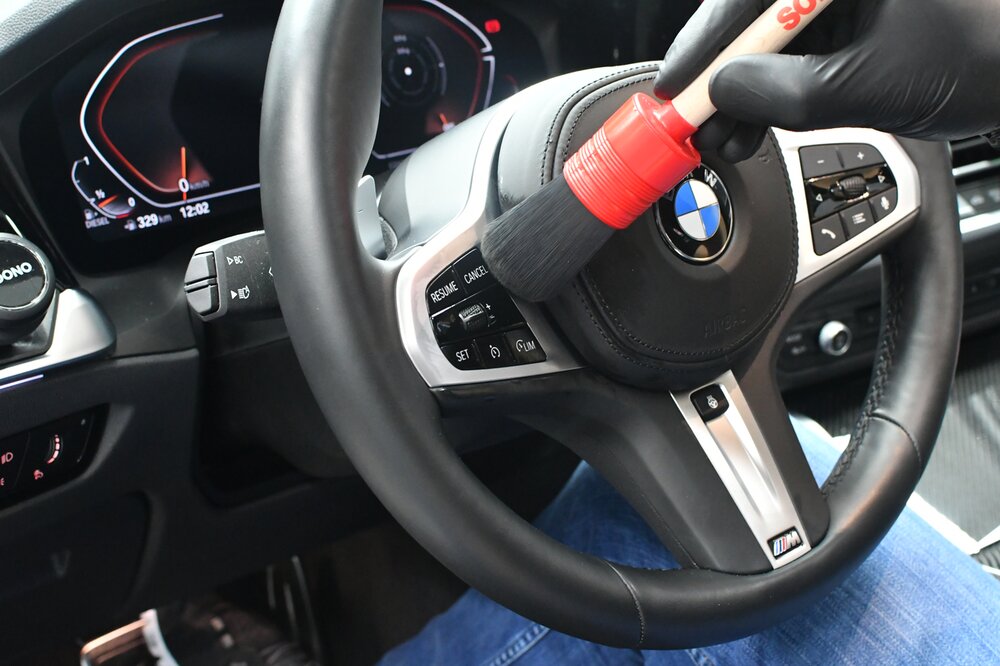 Jemand reinigt sein Lenkrad mit einem Pinsel.