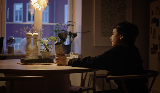 Child sitting alone at a kitchen table holding and looking at a milk carton
