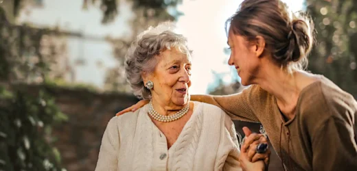 Elderly lady sits down and speaks to her younger female aged care worker