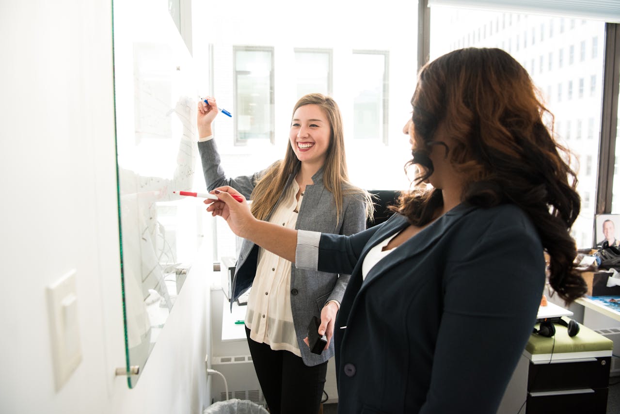 These lovely ladies are writing on a whiteboard the steps on how to become an executive assistant in Australia and the expected pay and salary