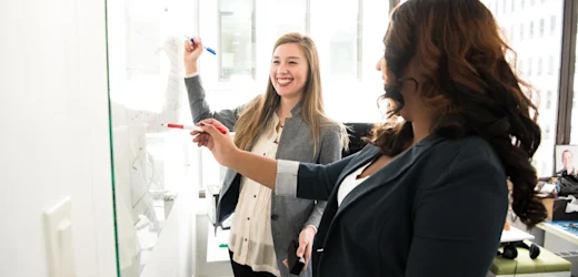 These lovely ladies are writing on a whiteboard the steps on how to become an executive assistant in Australia and the expected pay and salary