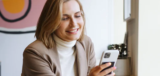 new female hire on first day of work with blonde hair smiles and checks mobile device