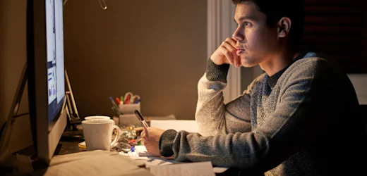 procurement manager in check business shirt at work taking notes with laptop open