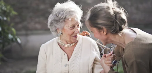 An elderly lady and a person sharing a special moment in a park, talking about how to become a support worker