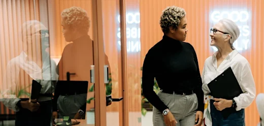 human resources and recruiting manager with clipboard speaks to potential candidate about HR role outside office with ‘Good vibes only’ neon sign in the background