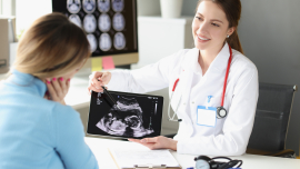 Doctor explaining ultrasound image to pregnant person