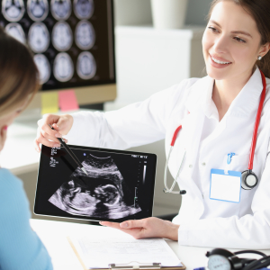 Doctor explaining ultrasound image to pregnant person