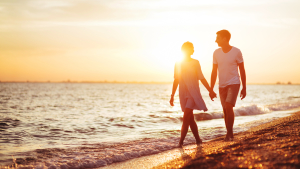 Couple walking on the beach at sunset or sunrise
