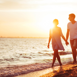 Couple walking on the beach at sunset or sunrise