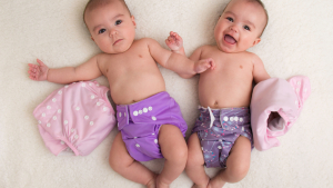 Two babies wearing colorful reusable diapers