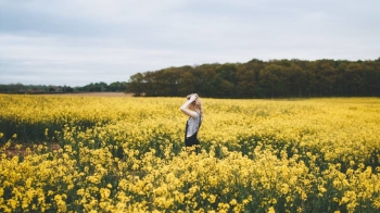 Woman walking in a field of rapeseed which makes seed oil