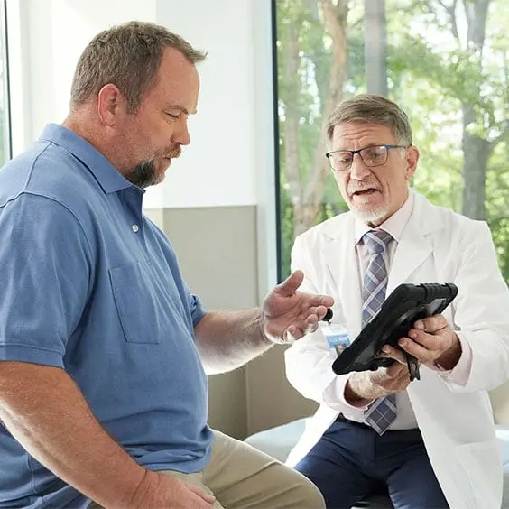 A doctor and patient conversing over a tablet.