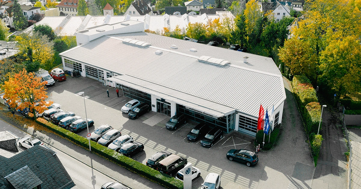 Eine Aufnahme des Volkswagen Autohauses in Königstein im Taunus, dass die Gebäude und Volkswagen Fahrzeuge vor dem Gebäude, sowie die Einfahrt zeigt.