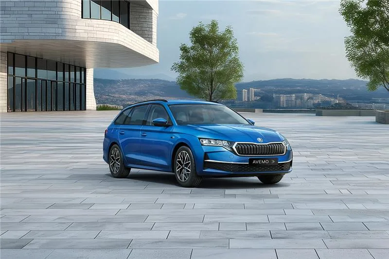 Skoda Octavia Sondermodell Balance Blauer Škoda Octavia Combi Balance steht auf einer modernen, weitläufigen Steinfläche vor einem futuristischen Gebäude mit großen Glasfronten; im Hintergrund Bäume und eine Stadtlandschaft.