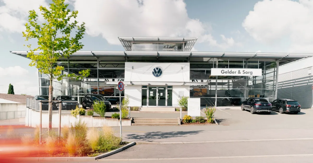 Eine Aufnahme des Volkswagen Autohauses in Coburg, die den Haupteingang des Gebäude und VW Fahrzeuge vor dem Gebäude zeigt.