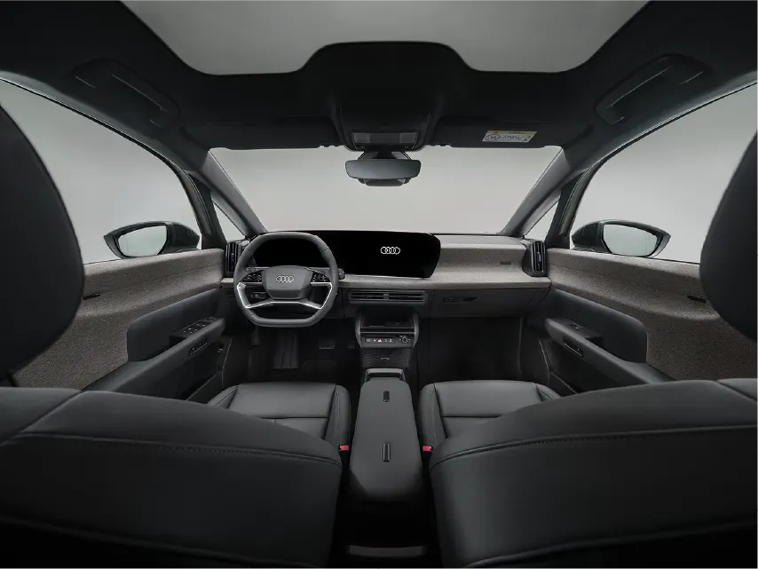 Blick von der Rückbank in den modernen Innenraum eines Audi mit schwarzer Lederausstattung, einem breiten Digitaldisplay am Armaturenbrett, minimalistischem Lenkrad und hellem Panoramadach.