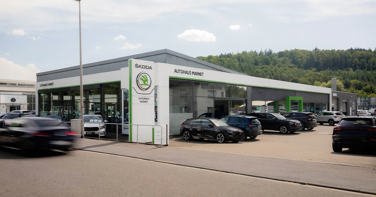 Eine Aufnahme des Škoda Autohauses in Heidenheim, die das Gebäude und Škoda Fahrzeuge vor dem Gebäude, sowie die Einfahrt zeigt.