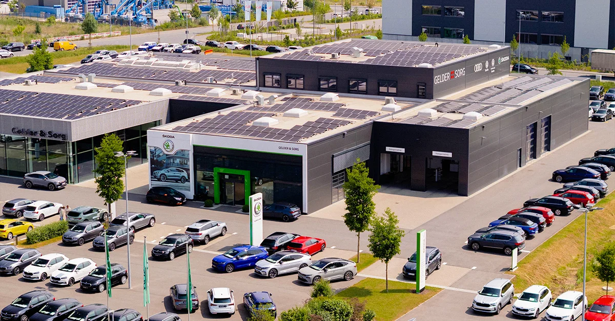 Eine Aufnahme des Škoda Autohauses in Schweinfurt, die das Gebäude, den Parkplatz und Škoda Fahrzeuge vor dem Gebäude zeigt.