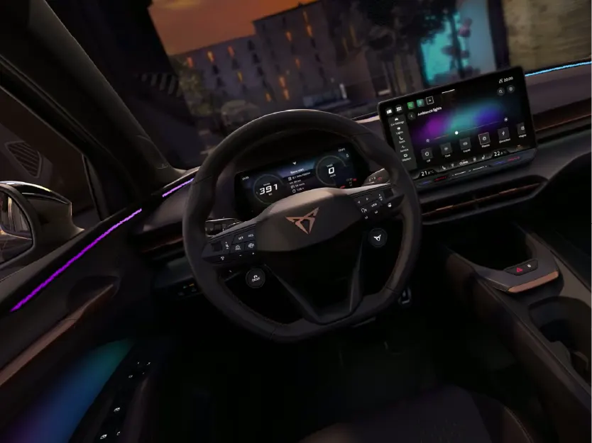Cockpit-Ansicht eines Cupra mit Fokus auf das sportliche Multifunktionslenkrad und das digitale Infotainment-System. Die violette Ambientebeleuchtung an den Türen und die kupferfarbenen Akzente unterstreichen das futuristische Design bei Nacht.