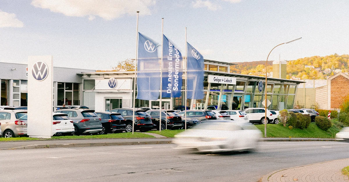 Eine Aufnahme des Volkswagen Autohauses in Linsengericht, die das Gebäude und Volkswagen Fahrzeuge vor dem Gebäude, sowie die Gelnhäuser Straße zeigt.