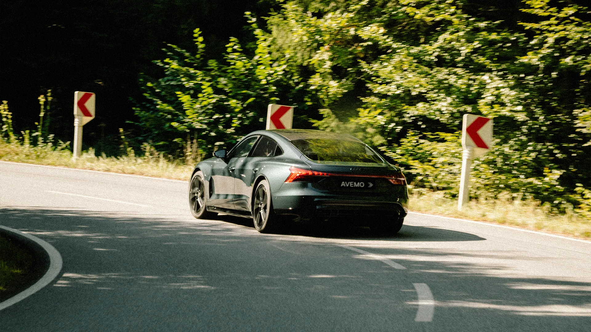 Eine Aufnahme eines Audi Fahrzeugs aus der Heckansicht. Das Fahrzeug fährt auf einer Landstraße in einer S-Kurve.