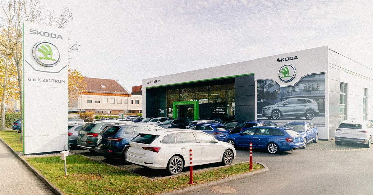 Eine Aufnahme des Škoda Autohauses in Hofheim am Taunus, die das Gebäude und Škoda Fahrzeuge vor dem Gebäude, sowie Parkplätze zeigt.