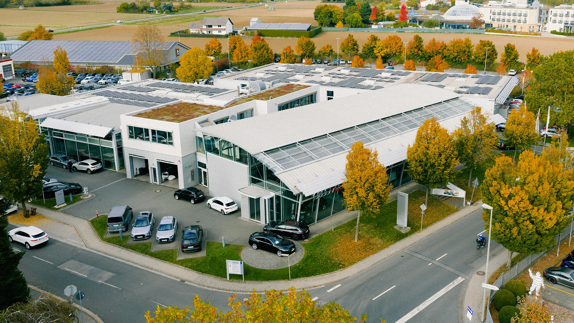Audi Zentrum Hofheim am Taunus Header Eine Aufnahme des Audi Zentrum Autohauses in Hofheim am Taunus, dass die Gebäude und Audi Fahrzeuge vor dem Gebäude zeigt.