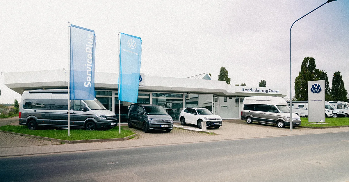 Eine Aufnahme des Volkswagen Nutzfahrzeuge Autohauses in Mühlheim am Main, die das Gebäude und Volkswagen Nutzfahrzeuge vor dem Gebäude zeigt.