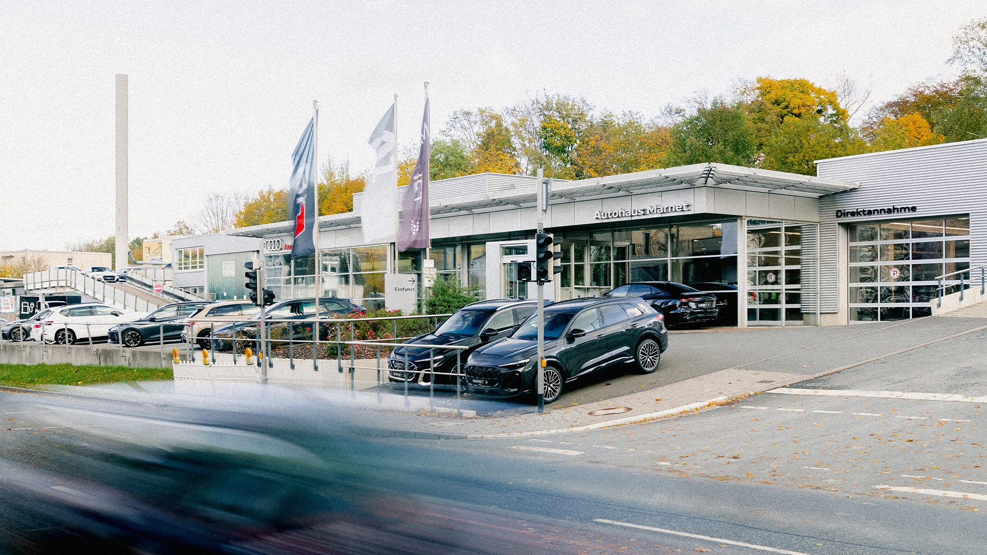 Audi Königstein im Taunus Header Eine Aufnahme des Audi Autohauses in Königstein im Taunus, dass die Gebäude und Audi Fahrzeuge vor dem Gebäude, sowie die Einfahrt zeigt.