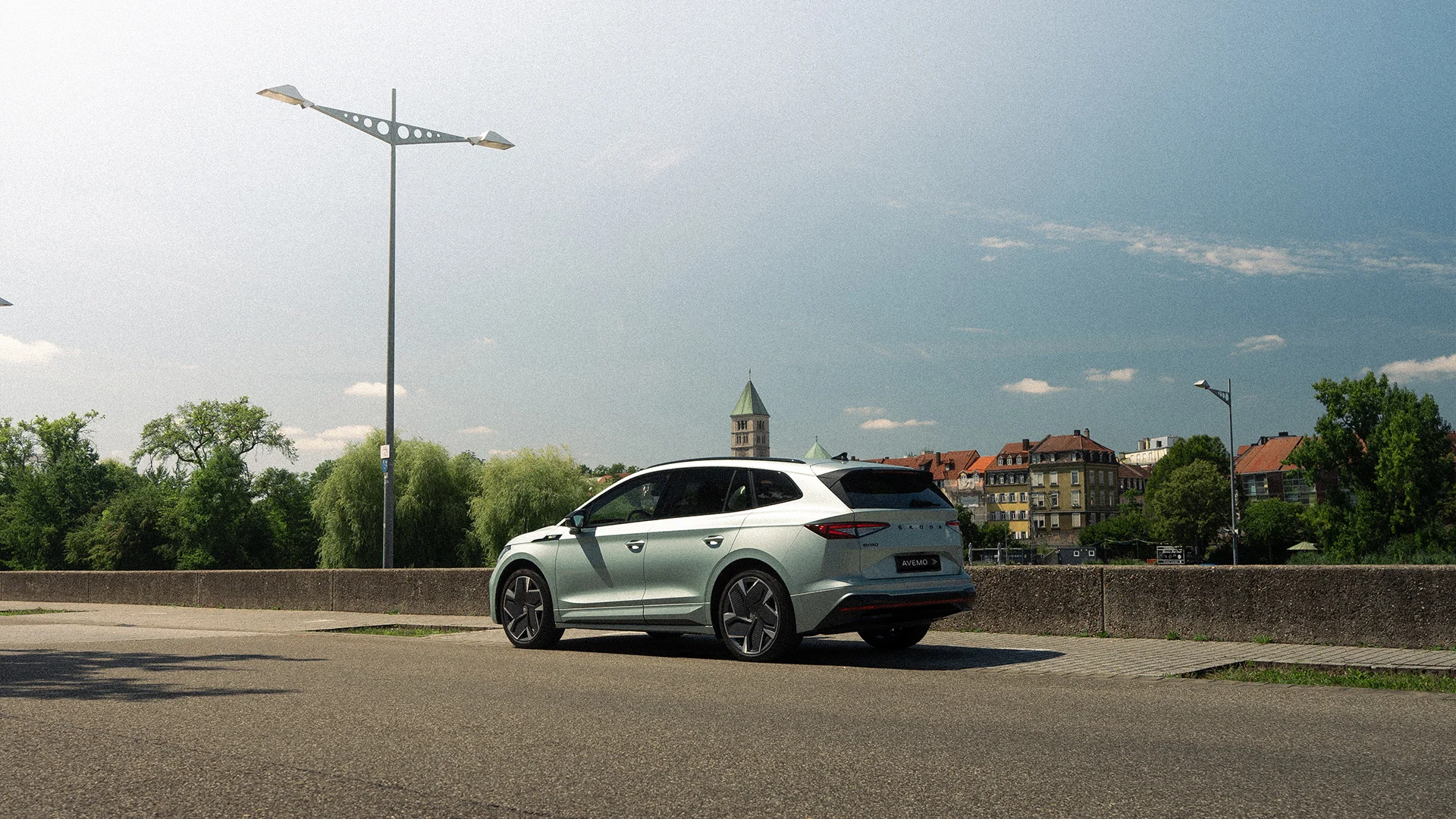 Eine Aufnahme eines Škoda SUVs, das parkende Auto und das Heck schräg von der Fahrerseite zeigt. Im Hintergrund ist eine Stadt zu erkennen.