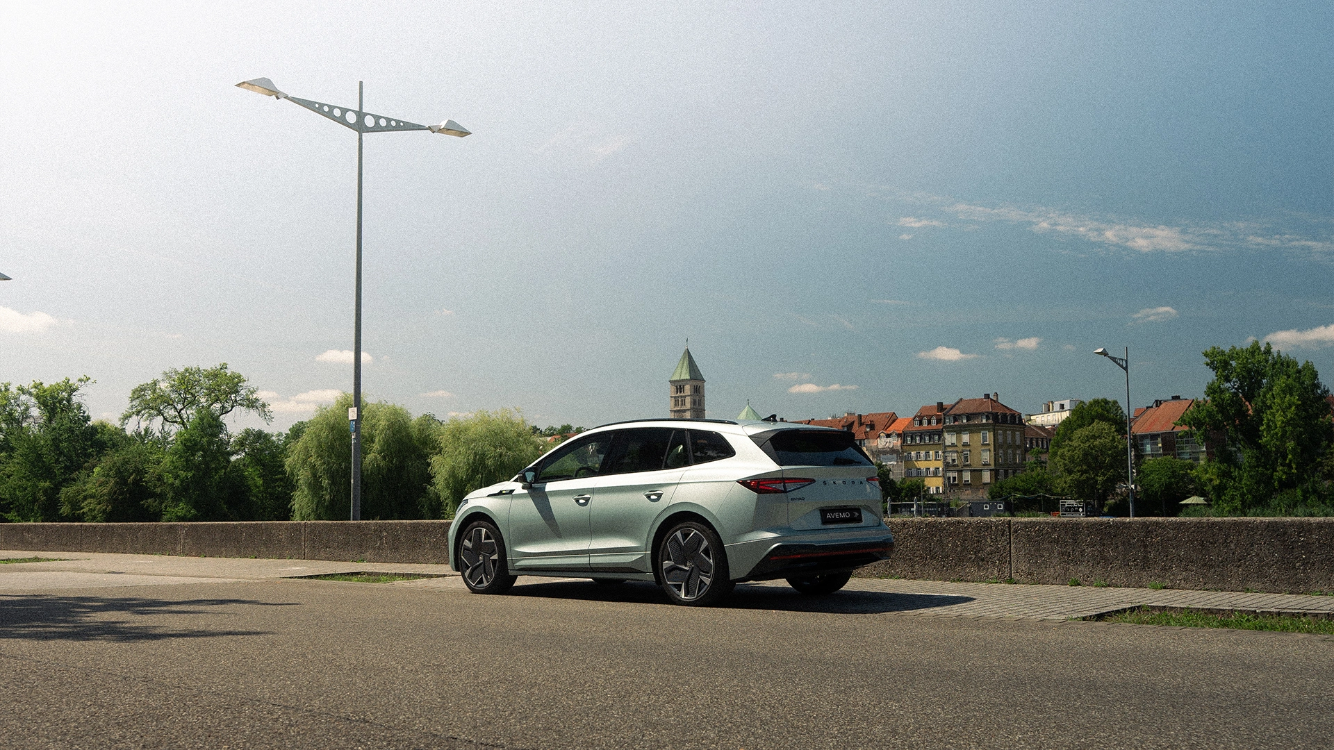 Eine Aufnahme eines Škoda SUVs, das parkende Auto und das Heck schräg von der Fahrerseite zeigt. Im Hintergrund ist eine Stadt zu erkennen.