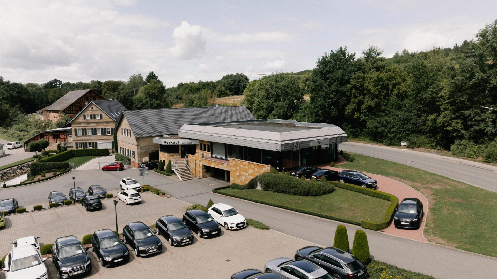 Ebern Header Eine Aufnahme des Autohauses in Ebern, dass das Gebäude und die Fahrzeuge vor dem Gebäude sowie die Einfahrt zeigt.