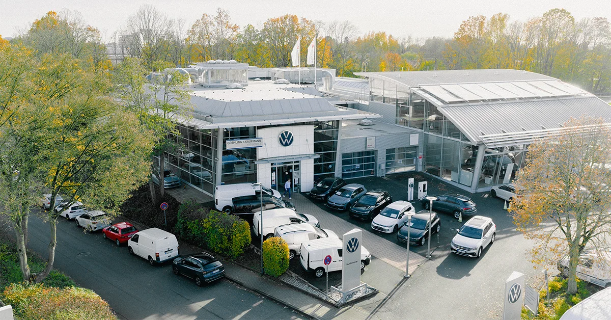 Eine Aufnahme des Volkswagen und Volkswagen Nutzfahrzeuge Autohauses in Eschborn, die das Gebäude und Volkswagen Fahrzeuge vor dem Gebäude, sowie die Einfahrt zeigt.