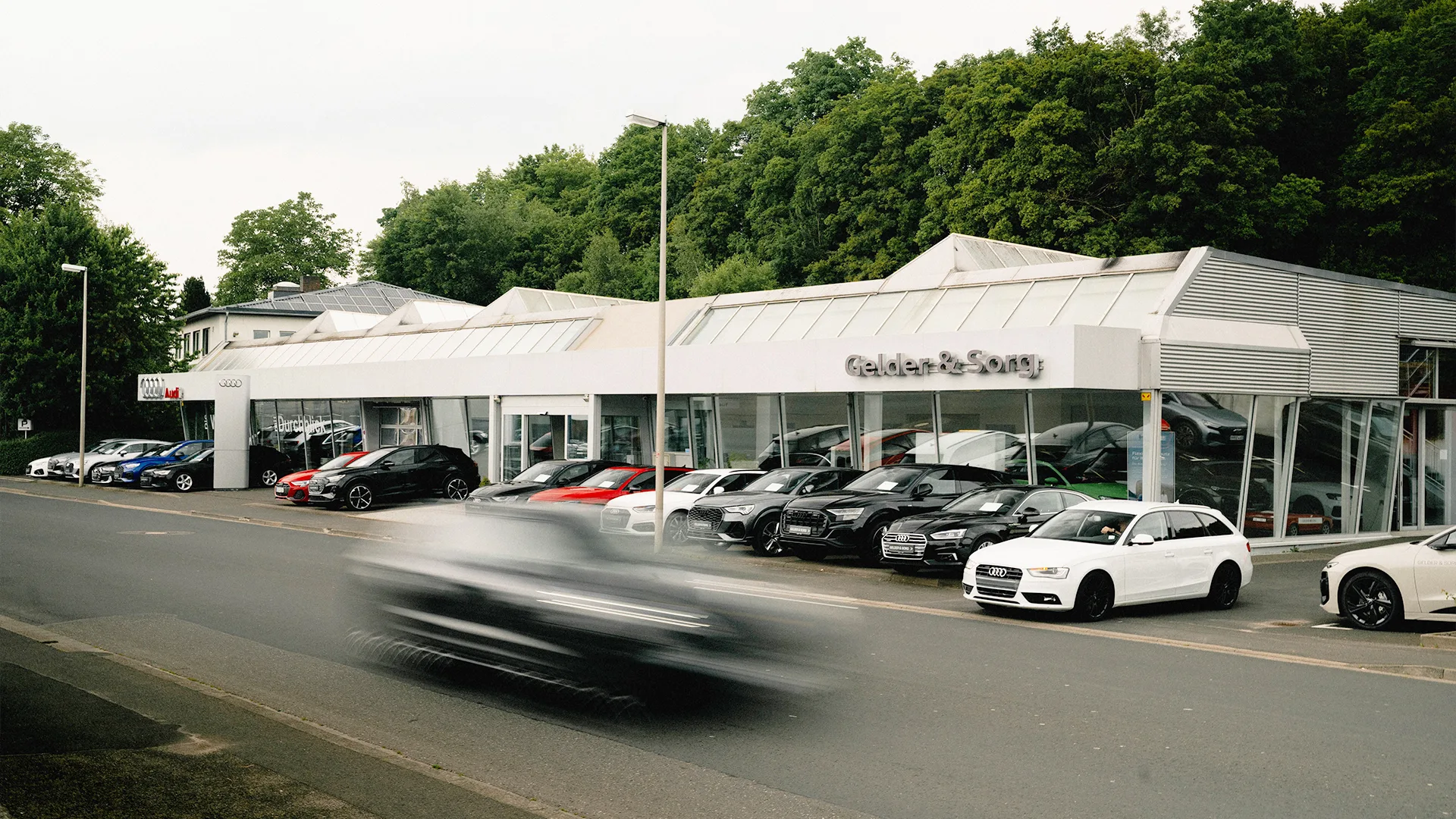 Eine Aufnahme des Audi Autohauses in Bad Kissingen, die das Gebäude sowie die Audi Fahrzeuge von der Würzburger Straße aus zeigt.