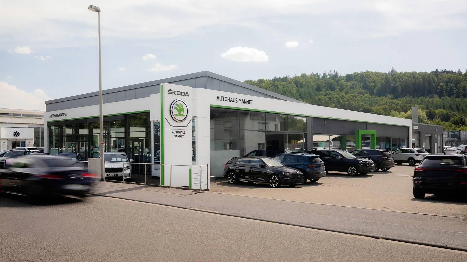 Eine Aufnahme des Škoda Autohauses in Heidenheim, dass das Gebäude und Škoda Fahrzeuge vor dem Gebäude, sowie die Einfahrt zeigt.