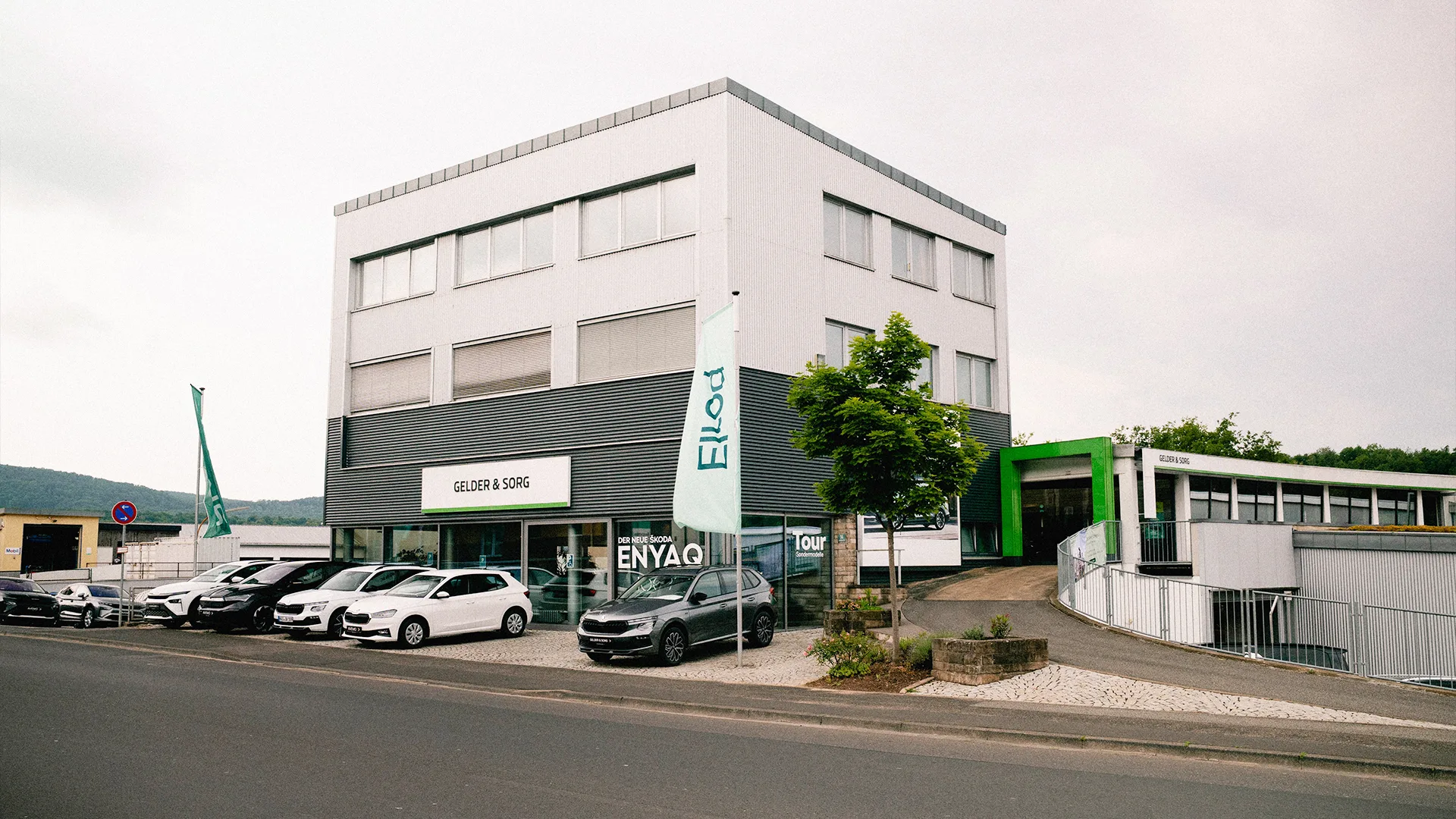 Eine Aufnahme des Škoda Autohauses in Bad Kissingen, die das Gebäude, den Haupteingang  sowie die Škoda Fahrzeuge vor dem Autohaus zeigt.