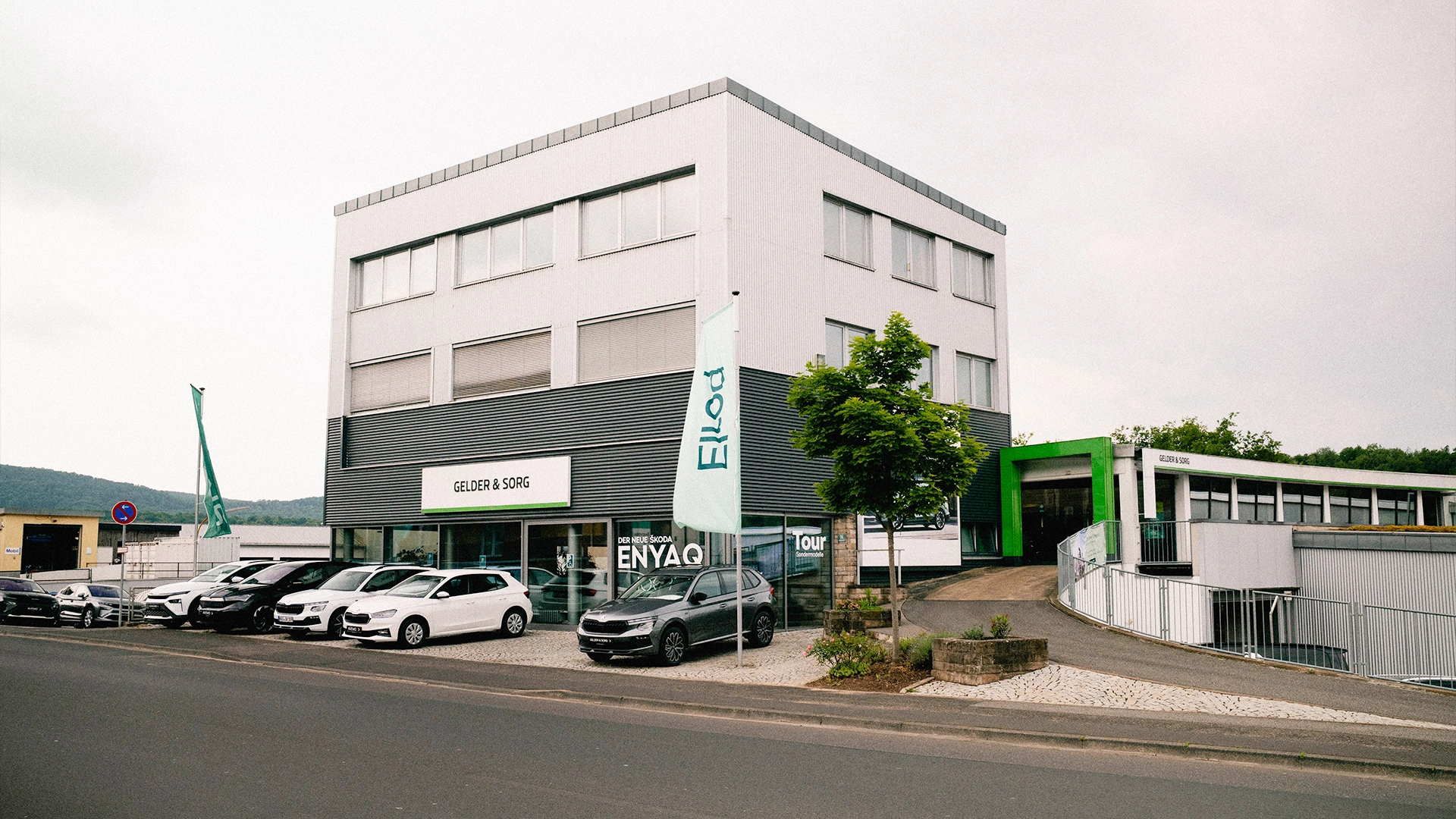 Eine Aufnahme des Škoda Autohauses in Bad Kissingen, die das Gebäude, den Haupteingang  sowie die Škoda Fahrzeuge vor dem Autohaus zeigt.
