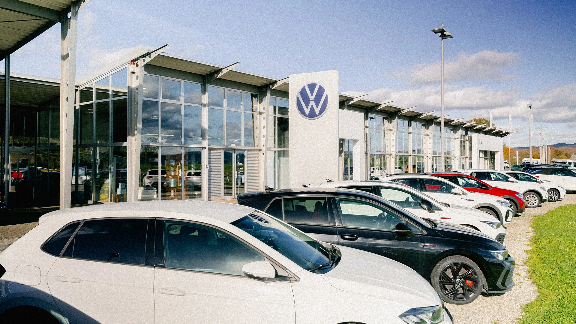 Eine Aufnahme des Volkswagen & Etrusco Autohauses in Büdingen, dass die Gebäude und Volkswagen Fahrzeuge vor dem Gebäude zeigt.