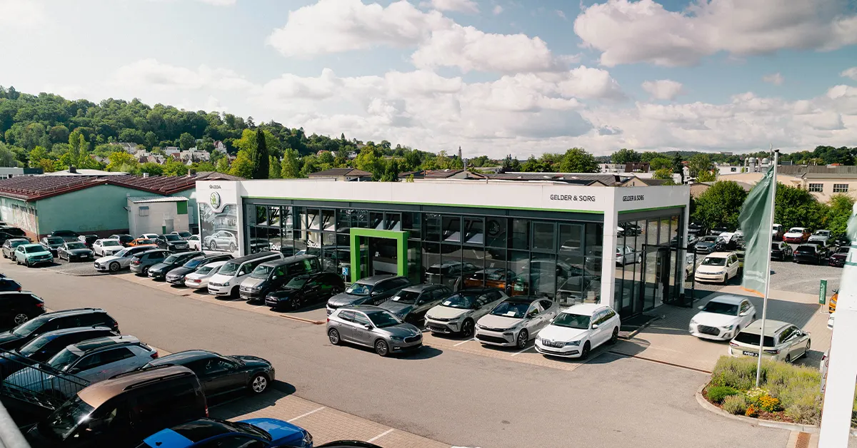 Eine Aufnahme des Škoda Autohauses in Coburg, die das Gebäude und Škoda Fahrzeuge vor dem Gebäude, sowie die Einfahrt zeigt.